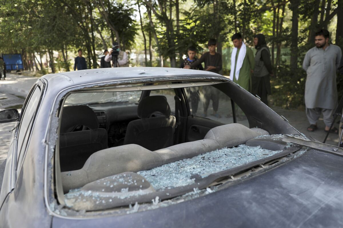 Afghan men look at a damage car after a roadside bomb explosion in Kabul, Afghanistan, Sunday, June 6, 2021. (AP Photo/Rahmat Gul)
