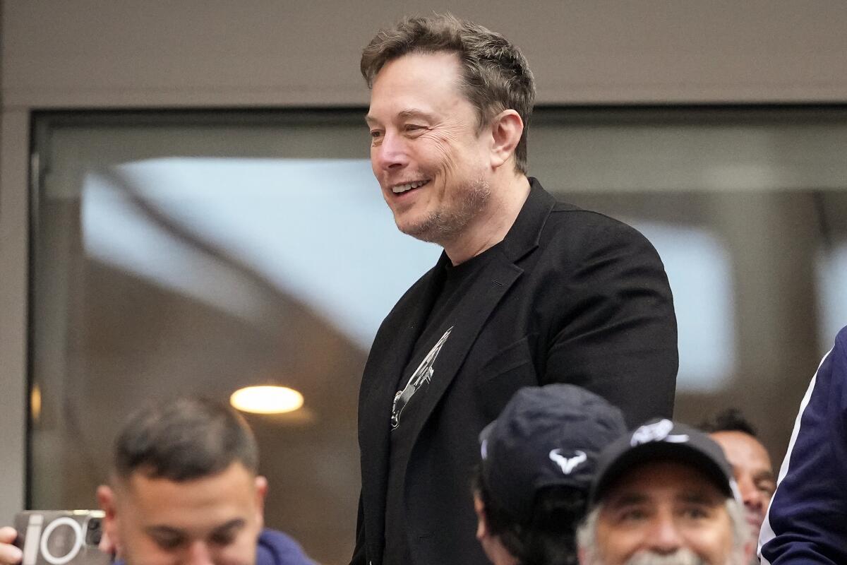 Elon Musk habla con otros espectadores mientras observa el partido 