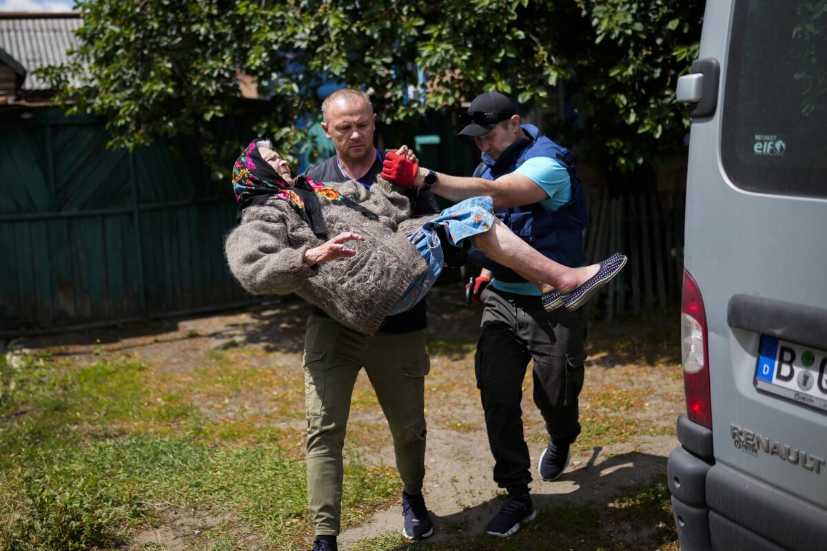Dos personas sacan a una mujer en brazos de su casa durante una evacuación 