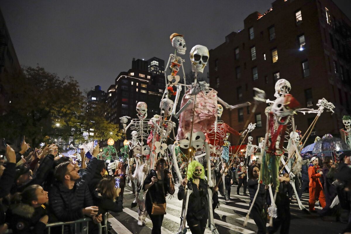 FILE - Revelers march during the Greenwich Village Halloween Parade in New York on Oct. 31, 2019. The holiday so many look forward to each year is going to look different in the pandemic as parents and the people who provide Halloween fun navigate a myriad of restrictions and safety concerns. (AP Photo/Frank Franklin II, File)