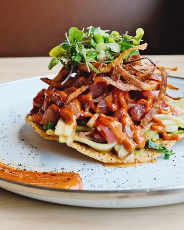 A tuna tostada with cucumbers and fried onions, and avocado sauce and chipotle aioli from Long Beach's Ruta 15 restaurant