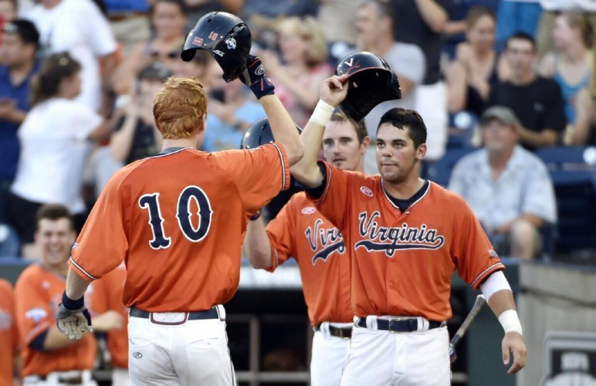 Virginia first baseman Pavin Smith (10) celebrates after hitting a two-run home, scoring teammate Kenny Towns, right, during the fourth inning of Game 3 of the College World Series finals.