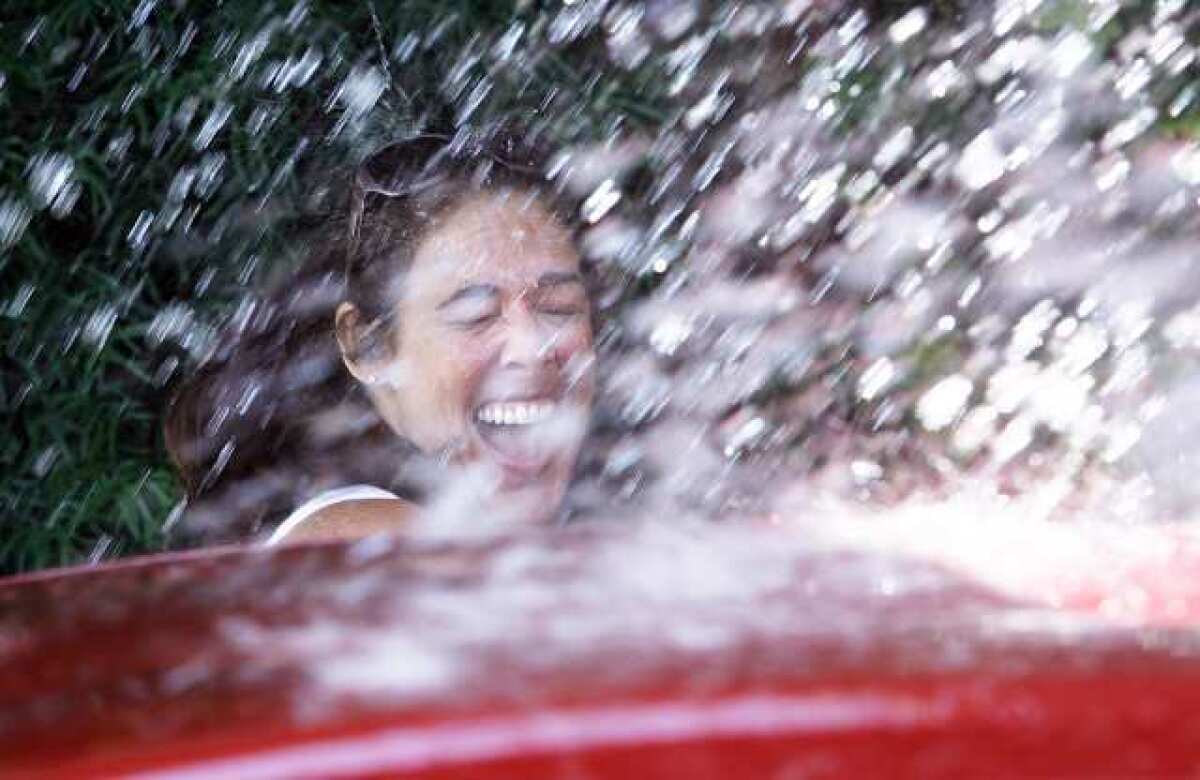 School principal Jay Schwartz laughs after calling for a rinse and not getting out of the way fast enough at a car wash fundraiser for College View School in Glendale.