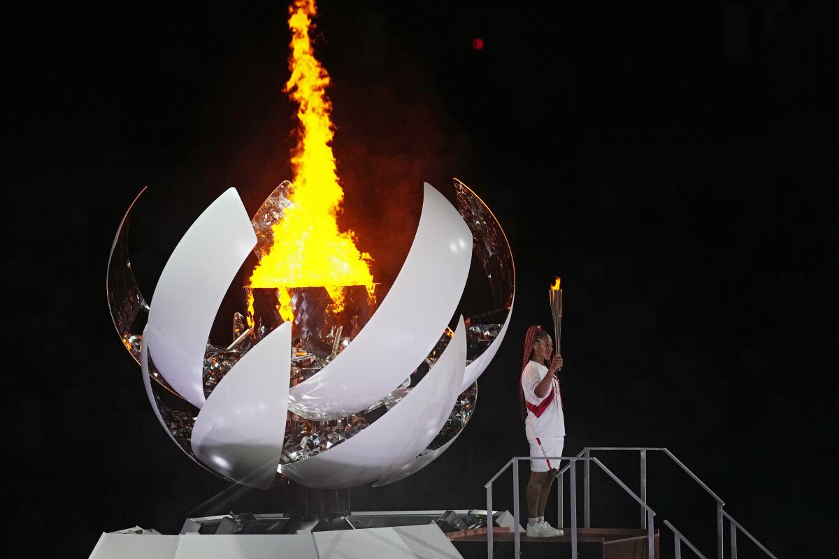 Naomi Osaka stands beside the Olympic flame during the opening ceremony at the 2020 Summer Olympics.