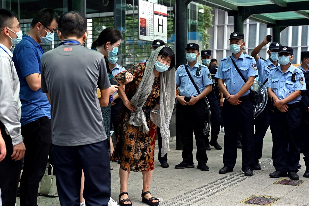 People gather outside the Evergrande headquarters building while police watch