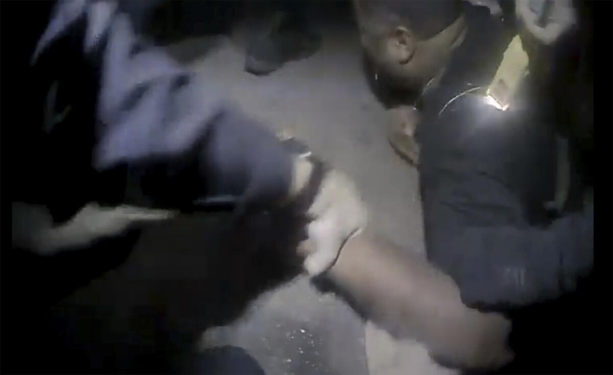 A screengrab shows a man facing downward while being held and stunned by police.