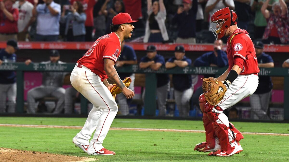 Angels pitcher Felix Pena celebrates with catcher Dustin Garneau after a combined no-hitter against the Mariners at Angel Stadium.