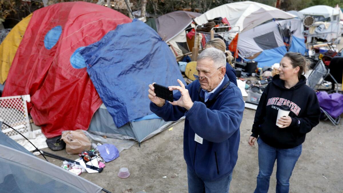 U.S. District Judge David Carter, shown with Brooke Weitzman, an attorney with the Santa Ana-based Elder Law and Disability Rights Center, surveys a large homeless encampment along the Santa Ana River in Anaheim on Feb. 14, 2018.