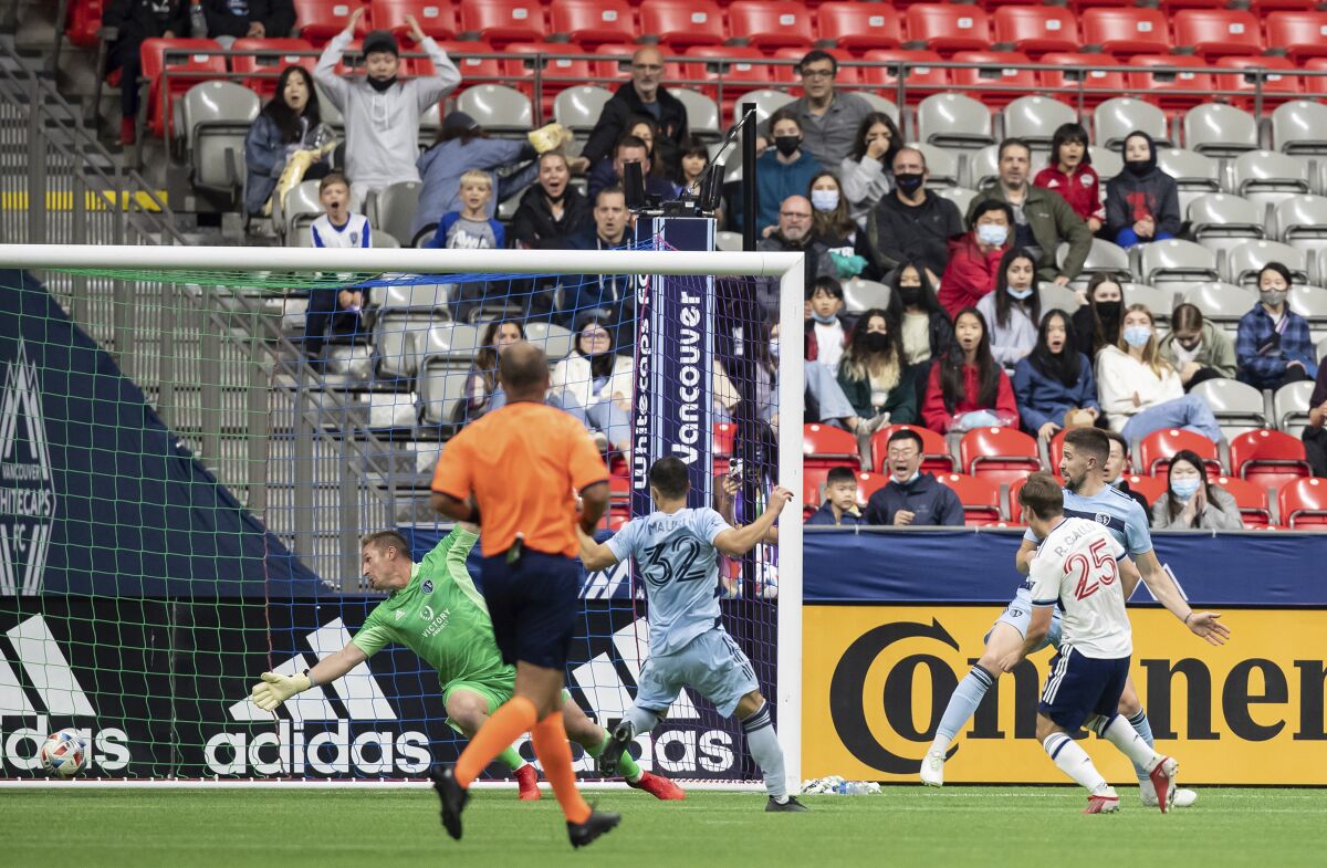 Vancouver Whitecaps' Ryan Gauld (25) scores against Sporting Kansas City goalkeeper Tim Melia, back left, during the first half of an MLS soccer match in Vancouver, British Columbia, Sunday, Oct. 17, 2021. (Darryl Dyck/The Canadian Press via AP)