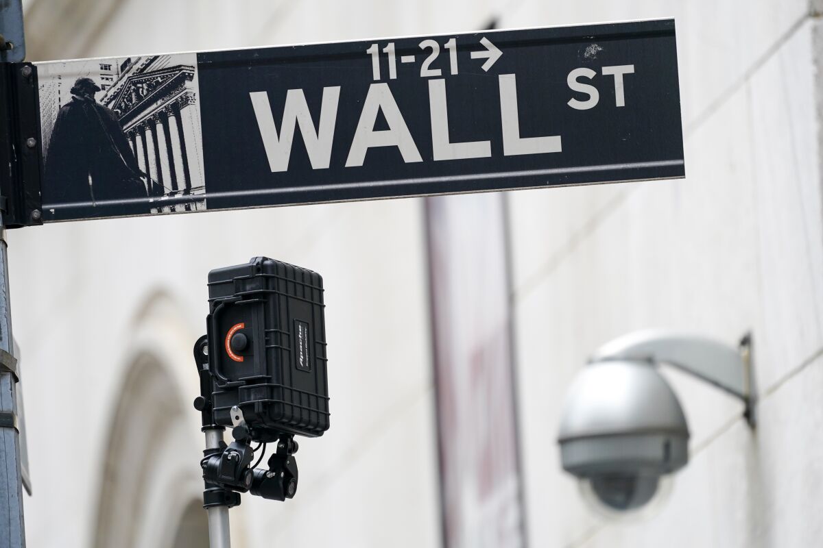 FILE - A Wall Street sign is seen next to surveillance equipment outside the New York Stock Exchange, Oct. 5, 2021, in New York. Stocks are opening lower on Wall Street Friday, Jan. 14, 2022 keeping the S&P 500 on course for its second weekly decline in a row. (AP Photo/Mary Altaffer, file)