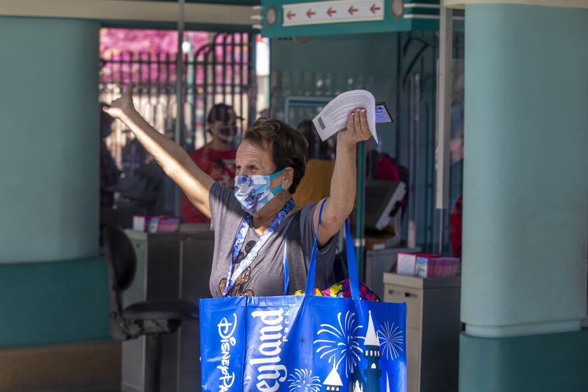 ANAHEIM, CA - March 18: After being shut down for over a year due to the Coronavirus pandemic, a Disney fan throws up her arms with excitement as she passes through the front gate to attend the debut of Disney California Adventure's "A Touch of Disney" food event at Disney California Adventure Park Thursday, March 18, 2021 in Anaheim, CA. This spans the entire DCA park and allows guests to eat, interact with characters and explore the grounds. A Touch of Disney, the new limited-time ticketed experience at Disney California Adventure Park which has sold out, takes place March 18 through April 19, 2021. (Allen J. Schaben / Los Angeles Times)