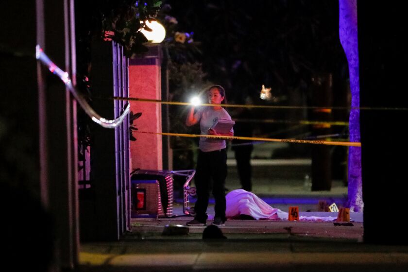 Investigators look over the body of a suspect at a scene after a shooting which left two officers and the suspect dead