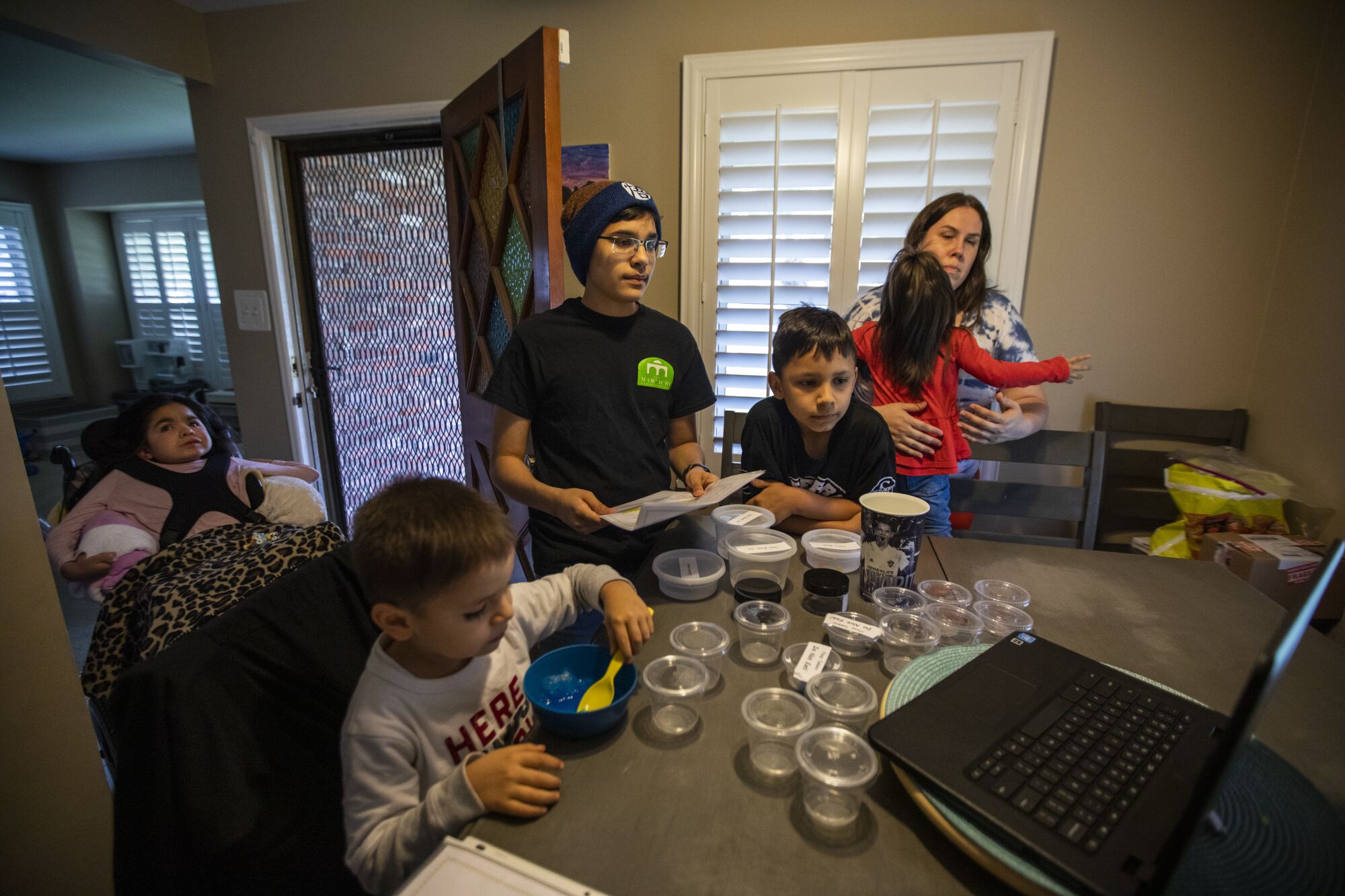 Hannah Lopez, far left, sits quietly as her siblings and mother participate in a Zoom science experiment.