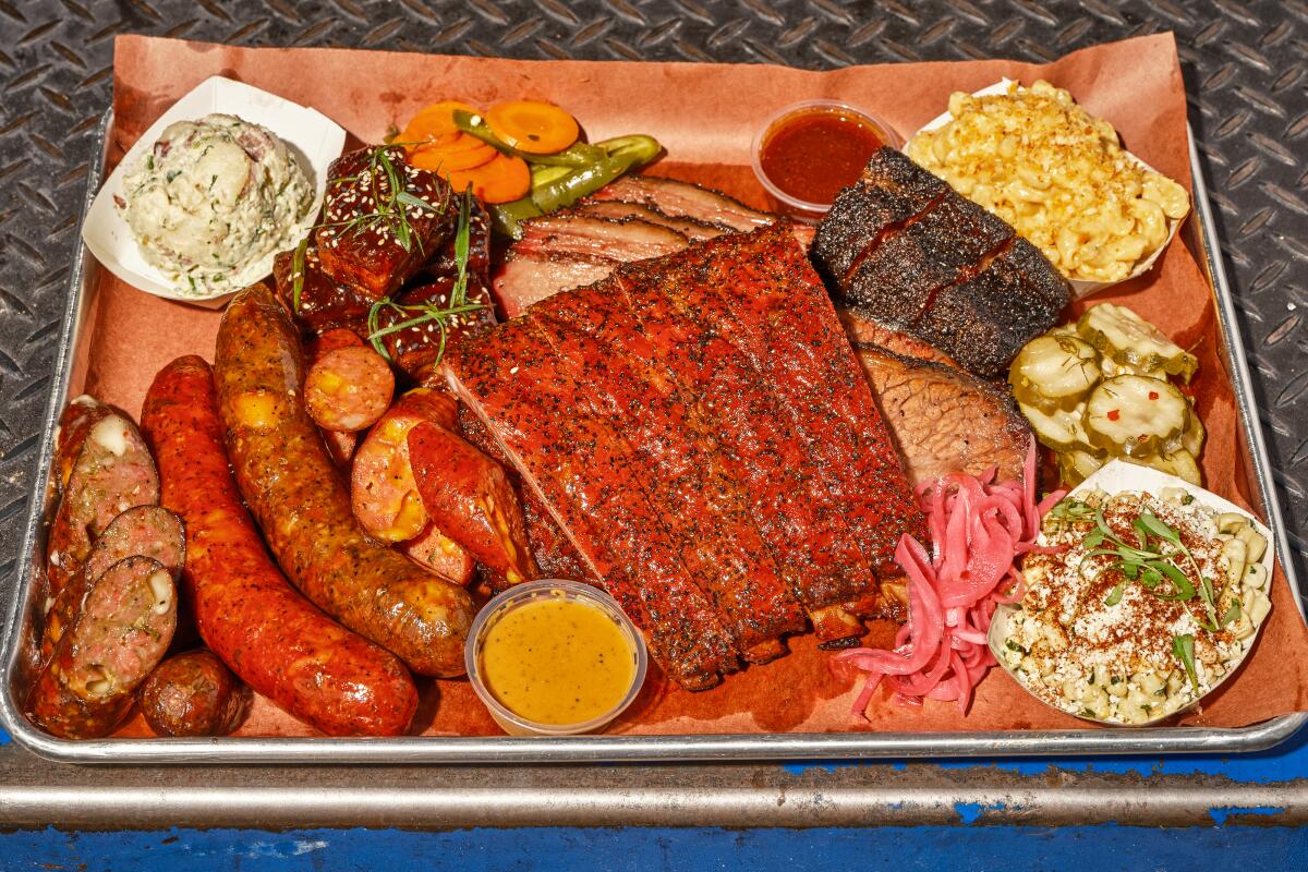 An overhead photo of a barbecue tray featuring ribs, sausages and sides from Moo's Craft Barbecue in Los Angeles
