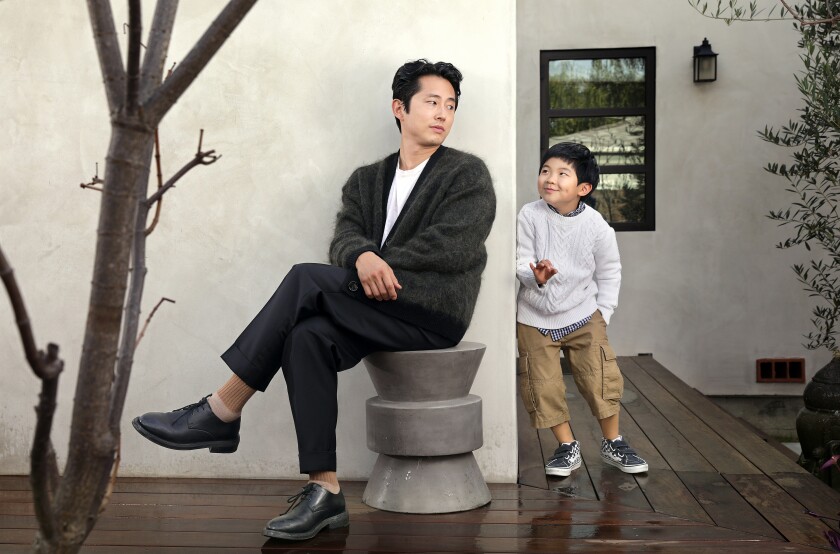 Steven Yeun sits outside while Alan Kim stands next to him