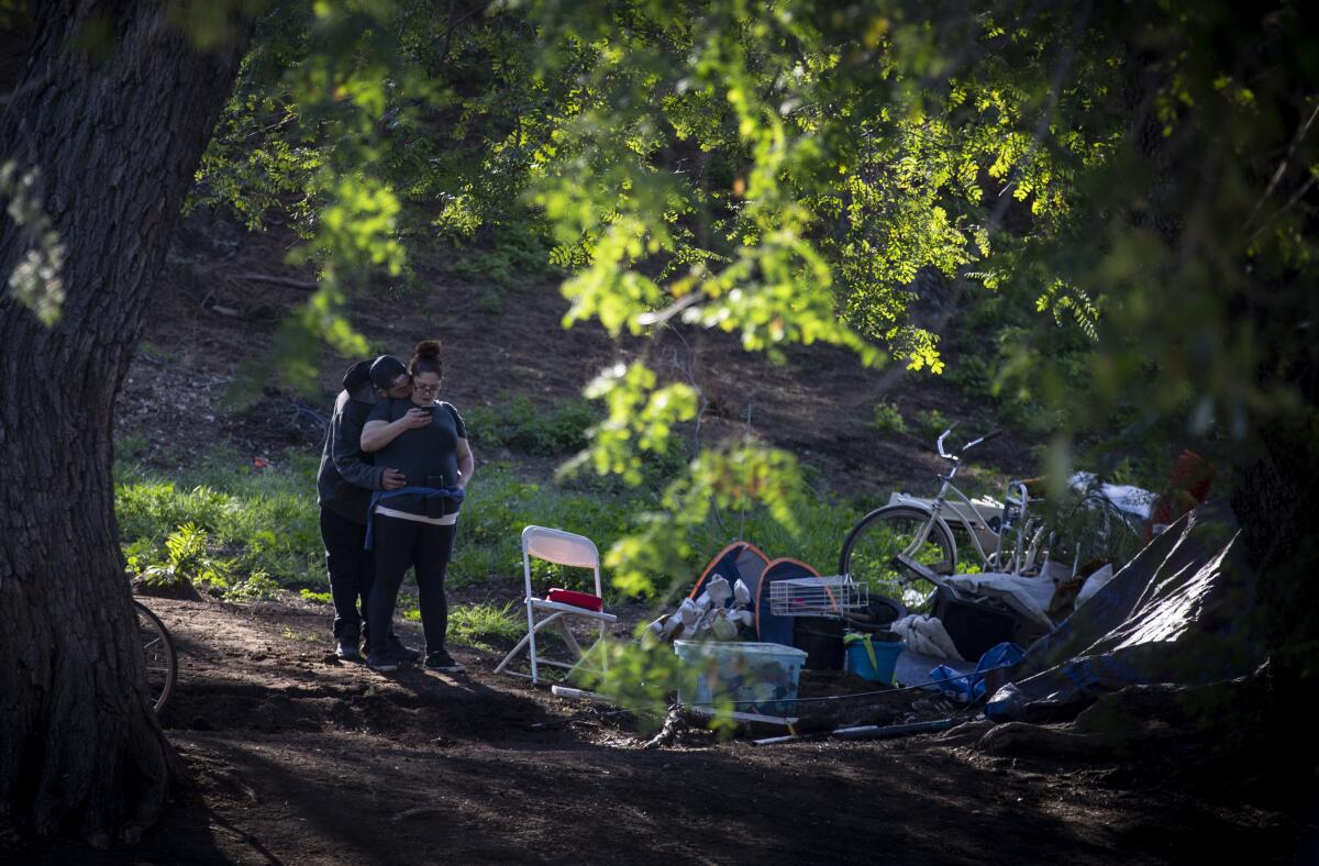A couple hug at an encampment at Lincoln Park, where many homeless people use mobile showers and hand-washing stations provided by volunteer groups such as Shower of Hope. At a time when frequent hand washing is considered a key to preventing the spread of the novel coronavirus, the closure of many businesses during stay-at-home orders has limited access to soap and water for homeless people.