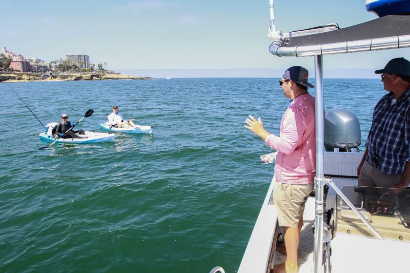 Cory Pukini (middle), WILDCOAST conservation coordinator and Joe Cooper (right), WILDCOAST contractor, speak with two people (left) who were fishing off of La Jolla Cove in the Matlahuayl MPA (Marine Protected Area) on August 9, 2019 in San Diego, California.