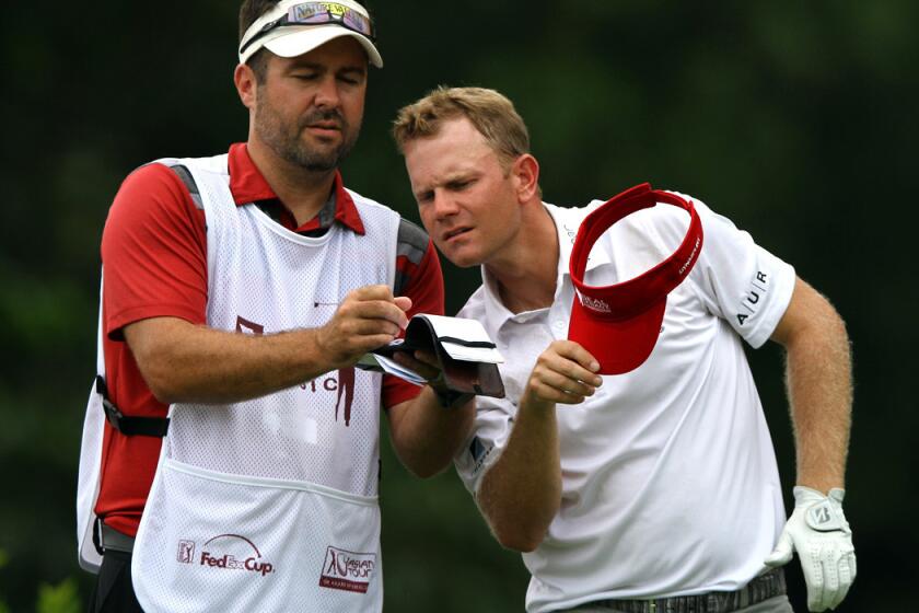 Billy Hurley III checks the yardage boox with his caddie at No. 7 on Friday during the second round of the CIMB Classic in Kuala Lumpur, Malaysia.