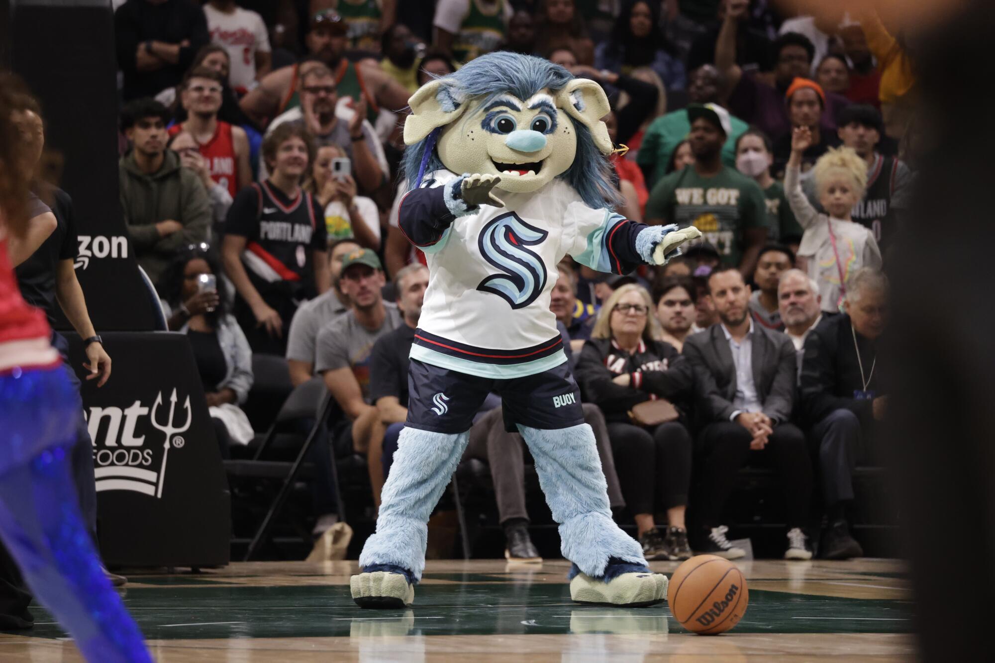 Buoy, the Seattle Kraken mascot, dances on the the basketball court during a timeout of a preseason game.