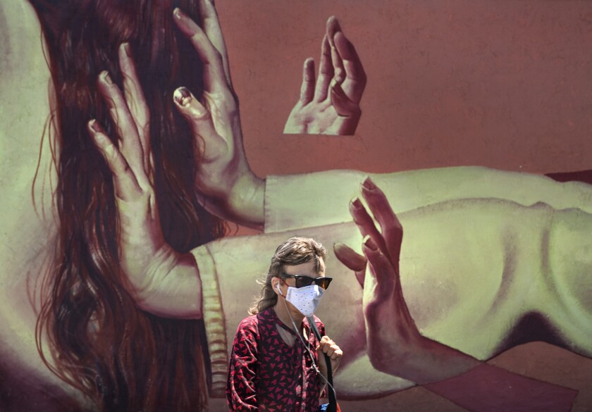 Caroline Kousidonis, 52, of Venice, wears a protective mask while walking past a mural on Lincoln Blvd. in Venice.