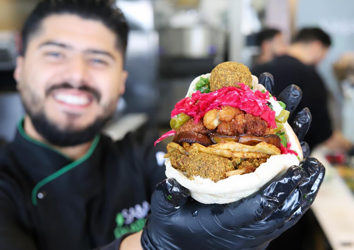 Mohammad Othman, 26, the co-owner of Sababa Falafel Shop holds the restaurant's famous falafel pita with vegetables.