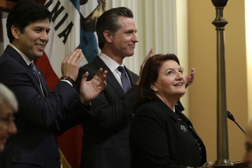 State Sen. Toni Atkins, D-San Diego, right, smiles up at the Senate Gallery after she was sworn in as the new Senate President pro tempore, Wednesday, March 21, 2018, in Sacramento, Calif. Atkins replaces former Senate President Pro Tem Kevin de Leon, D-Los Angeles, left. In the center is Lt. Gov. Gavin Newsom applauds Atkins, who becomes the first woman to lead the California Senate. (AP Photo/Rich Pedroncelli)