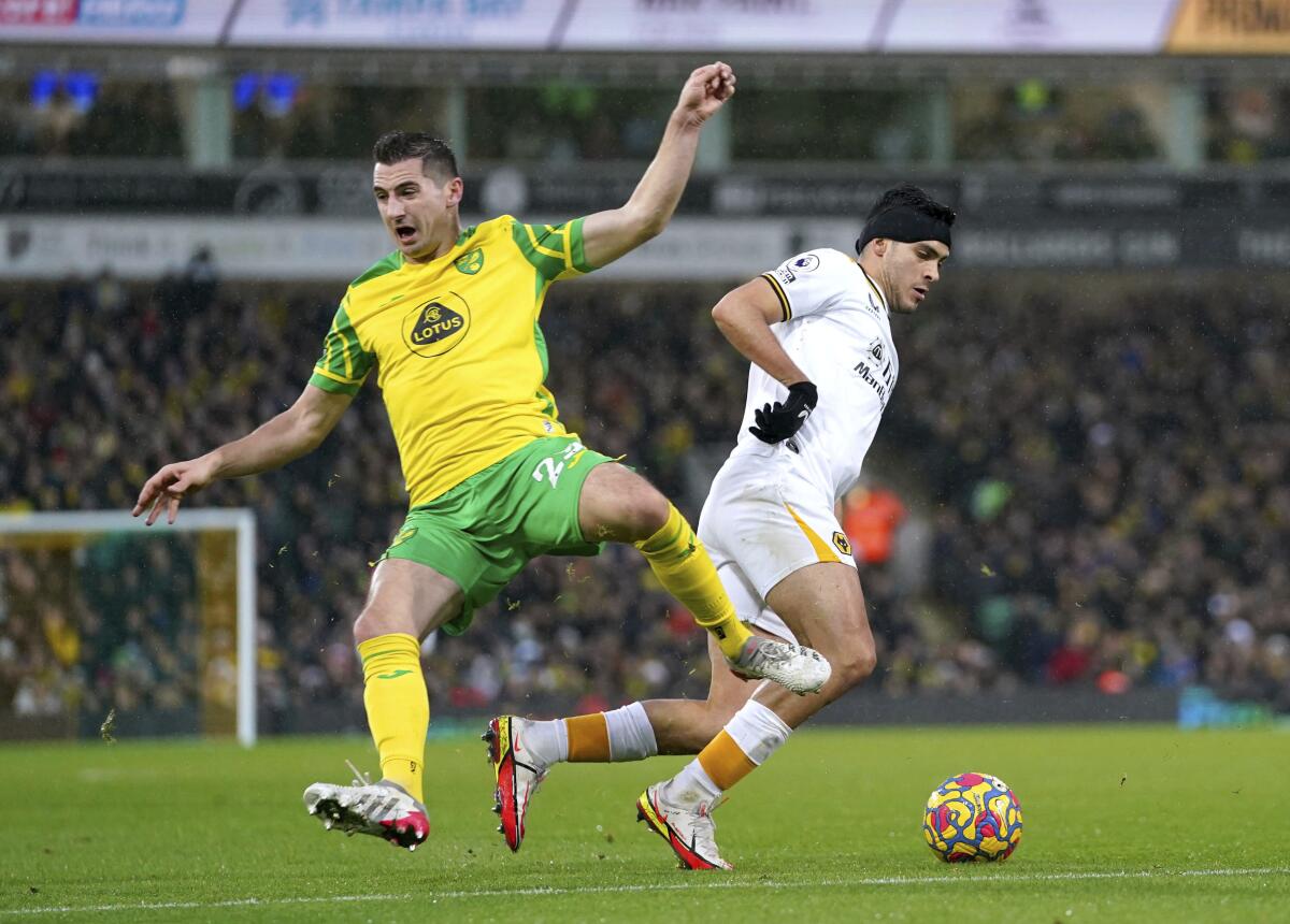 Norwich City's Kenny McLean, left, and Wolverhampton Wanderers' Raul Jimenez battle for the ball during the English Premier League soccer match between Norwich City and Wolverhampton Wanderers at Carrow Road, Norwich, England, Saturday Nov. 27, 2021. (Joe Giddens/PA via AP)