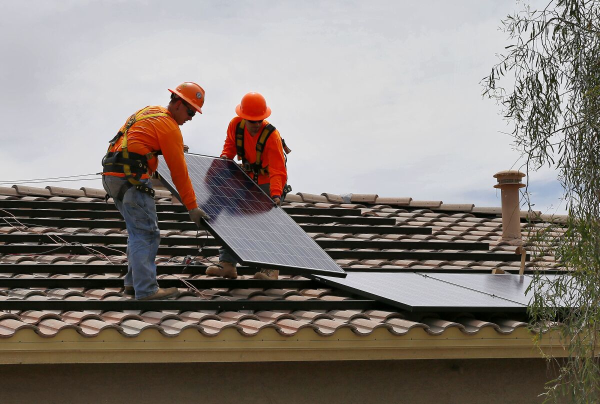 Electricians install solar panels on a roof