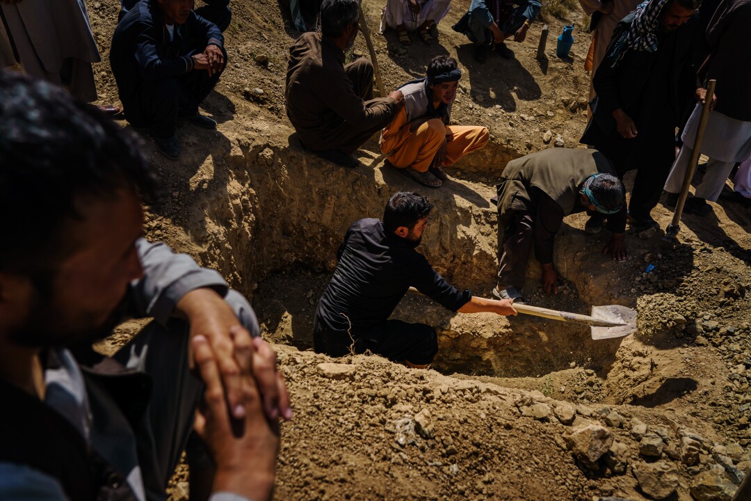 People dig a grave on a hillside.