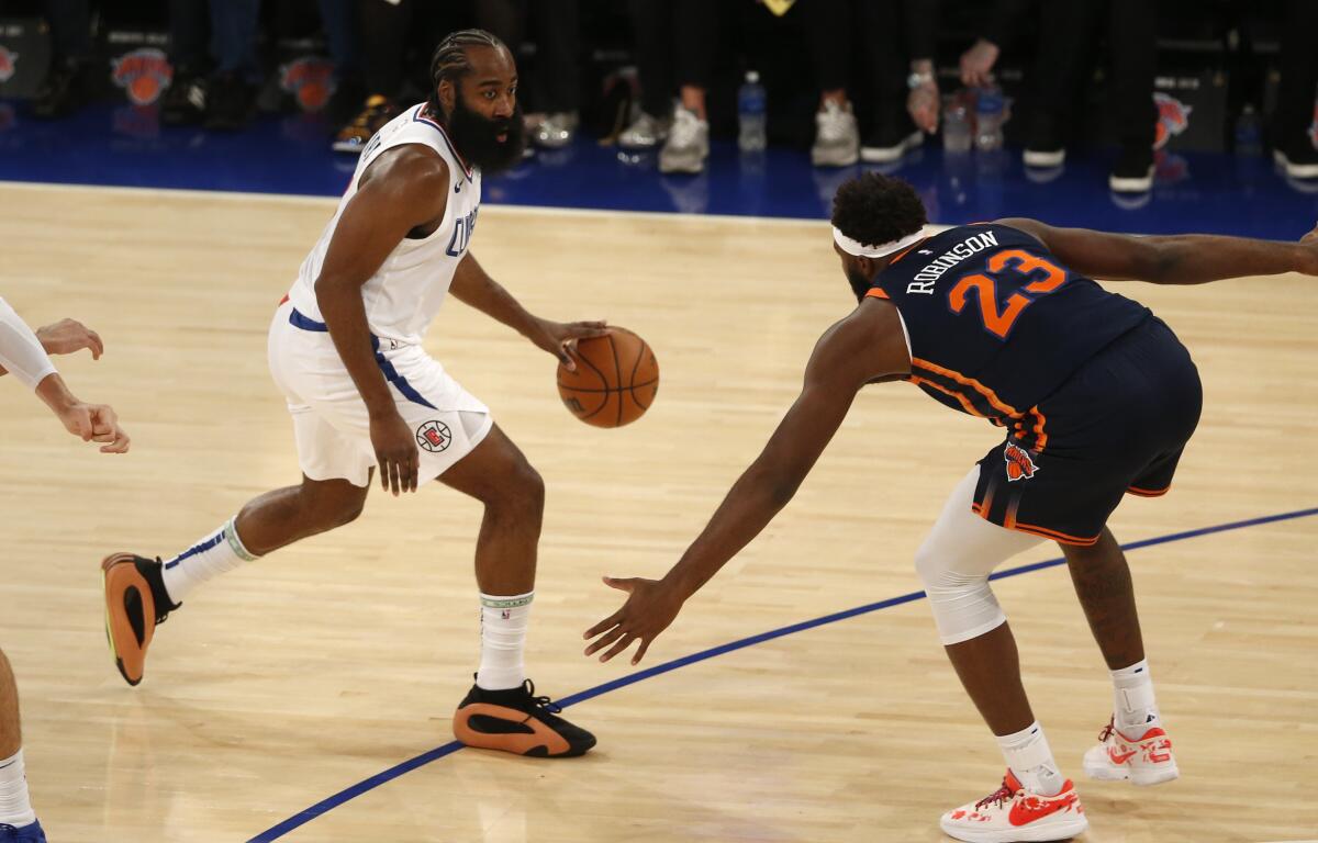 Clippers guard James Harden controls the ball in front of New York Knicks center Mitchell Robinson.