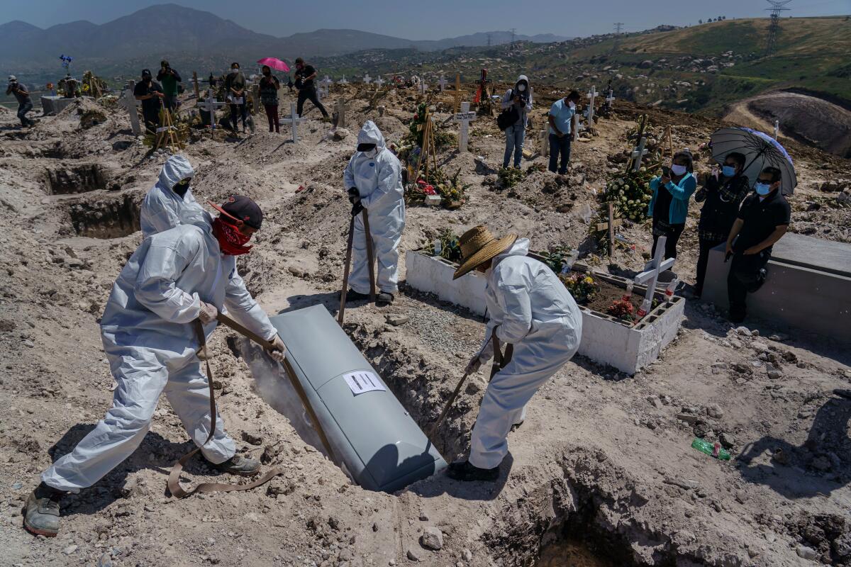 Cemetery workers lower the casket of Juan Velasco, who died with COVID-19 symptoms, April 27 at a cemetery in Tijuana.