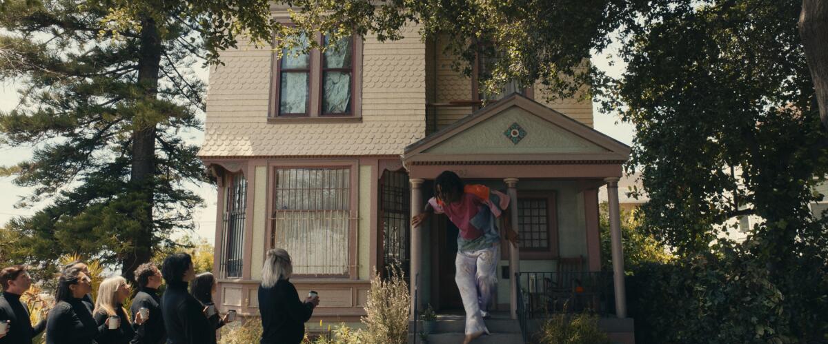A 13-foot-tall person emerges from the front door of a Victorian house in "I'm a Virgo."