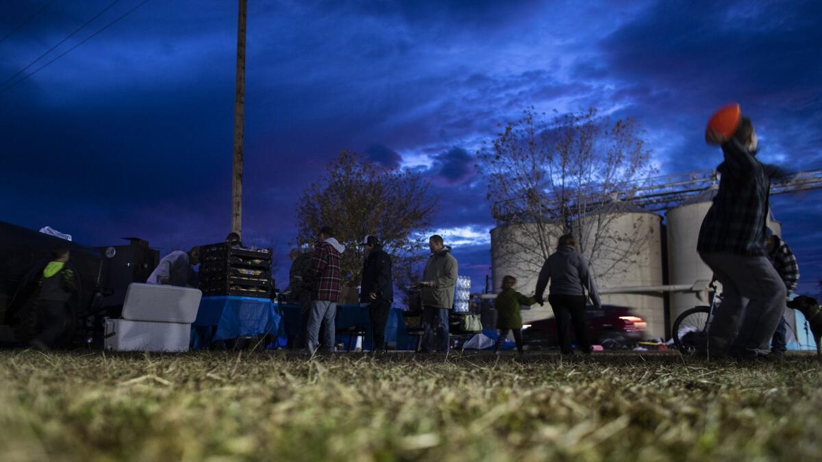 Camp fire evacuee Nathan Thomas II, 7, of Paradise tosses a football as his family walks to get in line for a free meal.