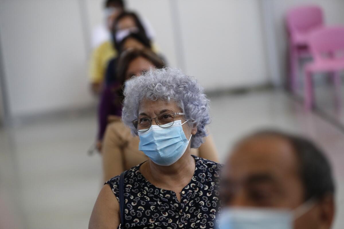 Personas esperan en el área de recuperación después de ser vacunadas con la vacuna de Johnson & Johnson en un centro de inoculación operado por las fuerzas armadas portuguesas en el estadio deportivo de la Universidad de Lisboa el miércoles 23 de junio de 2021. (AP Foto/Armando Franca)