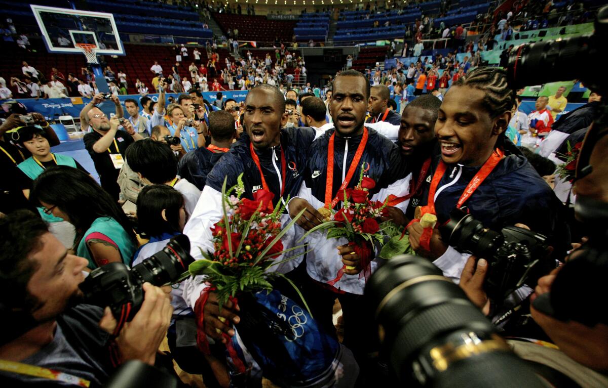 FILE - Kobe Bryant, from left, LeBron James, Dwyane Wade and Carmelo Anthony, of the U.S. Olympic basketball team, are surrounded by photographers as they celebrate after beating Spain 118-107 in the men's gold medal basketball game at the Beijing 2008 Olympics in Beijing. A documentary on the 2008 U.S. men’s basketball team known as the “Redeem Team,” with executive producers including Lebron James and Dwayne Wade, will premiere on Netflix in October. (AP Photo/Dusan Vranic, File)
