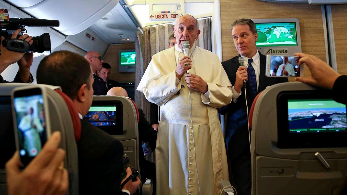 Pope Francis talks to reporters aboard the plane for his trip to Chile and Peru.