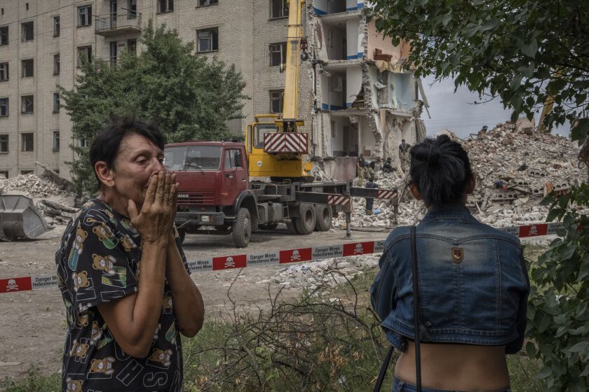 Iryna Shulimova, 59, weeps at the scene in the aftermath of a Russian rocket that hit an apartment residential block, in Chasiv Yar, Donetsk region, eastern Ukraine, Sunday, July 10, 2022. At least 15 people were killed and more than 20 people may still be trapped in the rubble, officials said Sunday. (AP Photo/Nariman El-Mofty)
