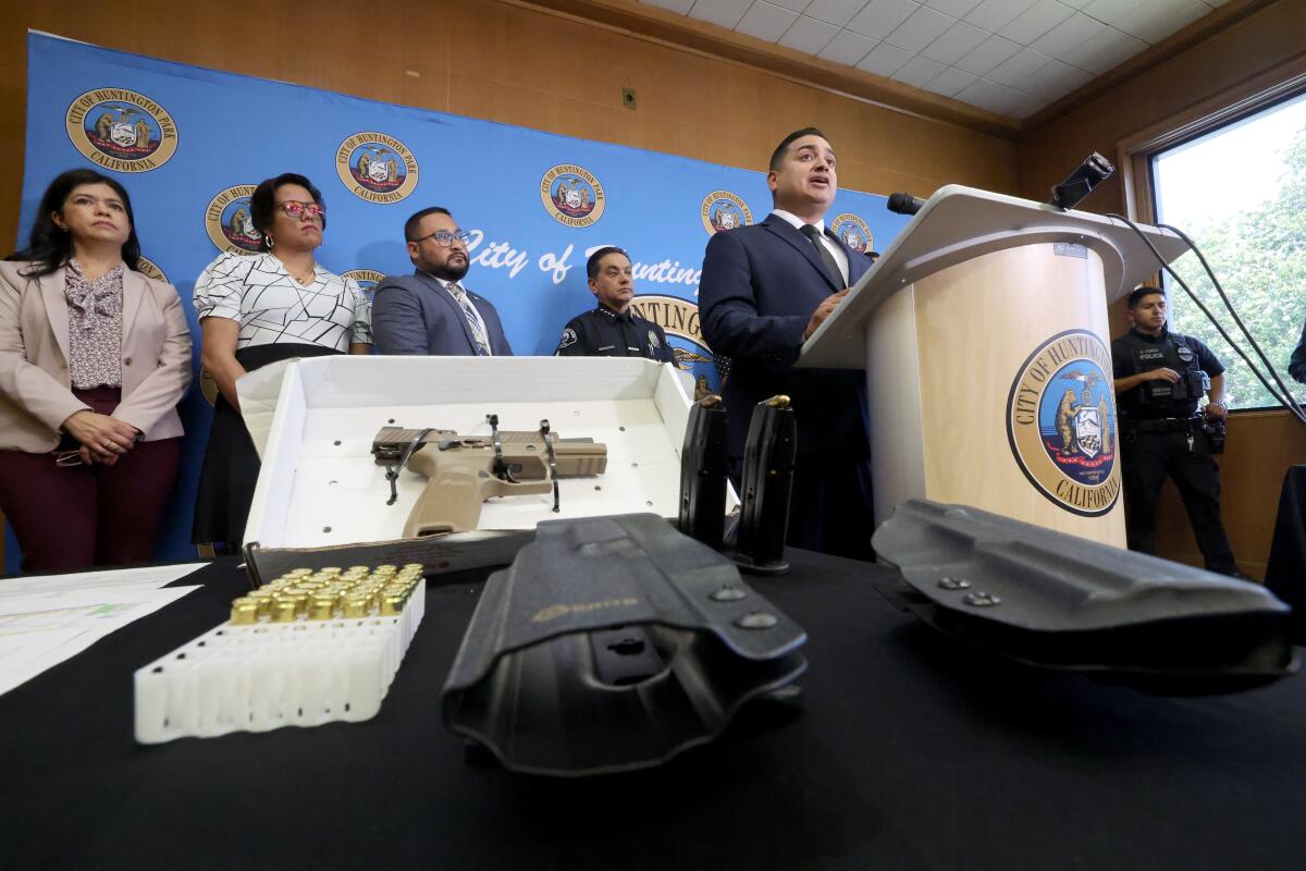 A semi-automatic firearm and holster is displayed as Huntington Park Mayor Arturo Flores speaks.
