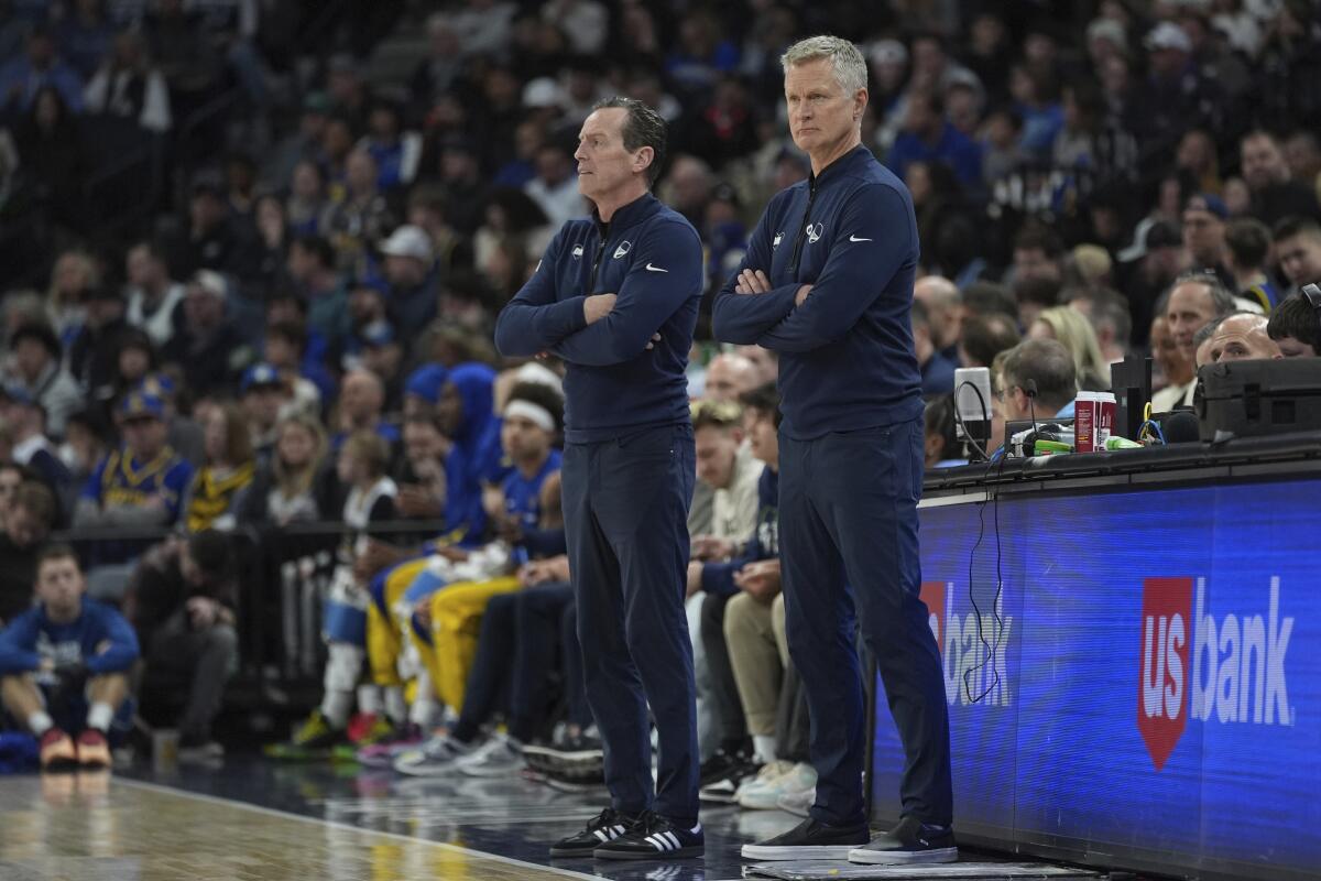 Warriors head coach Steve Kerr, right, and assistant Kenny Atkinson watch play while standing along the sideline.