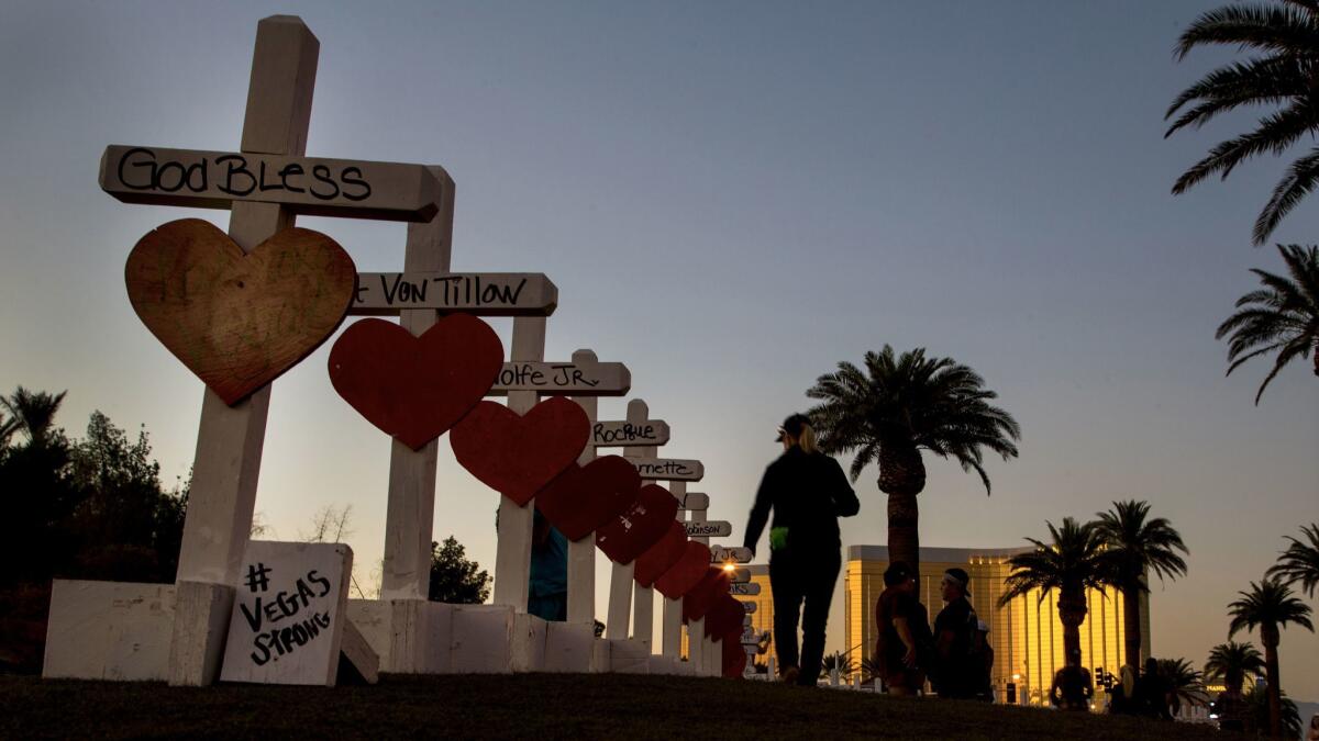 A woman walks beside 58 white crosses for the victims of the Oct. 1 mass shooting on the Las Vegas Strip.