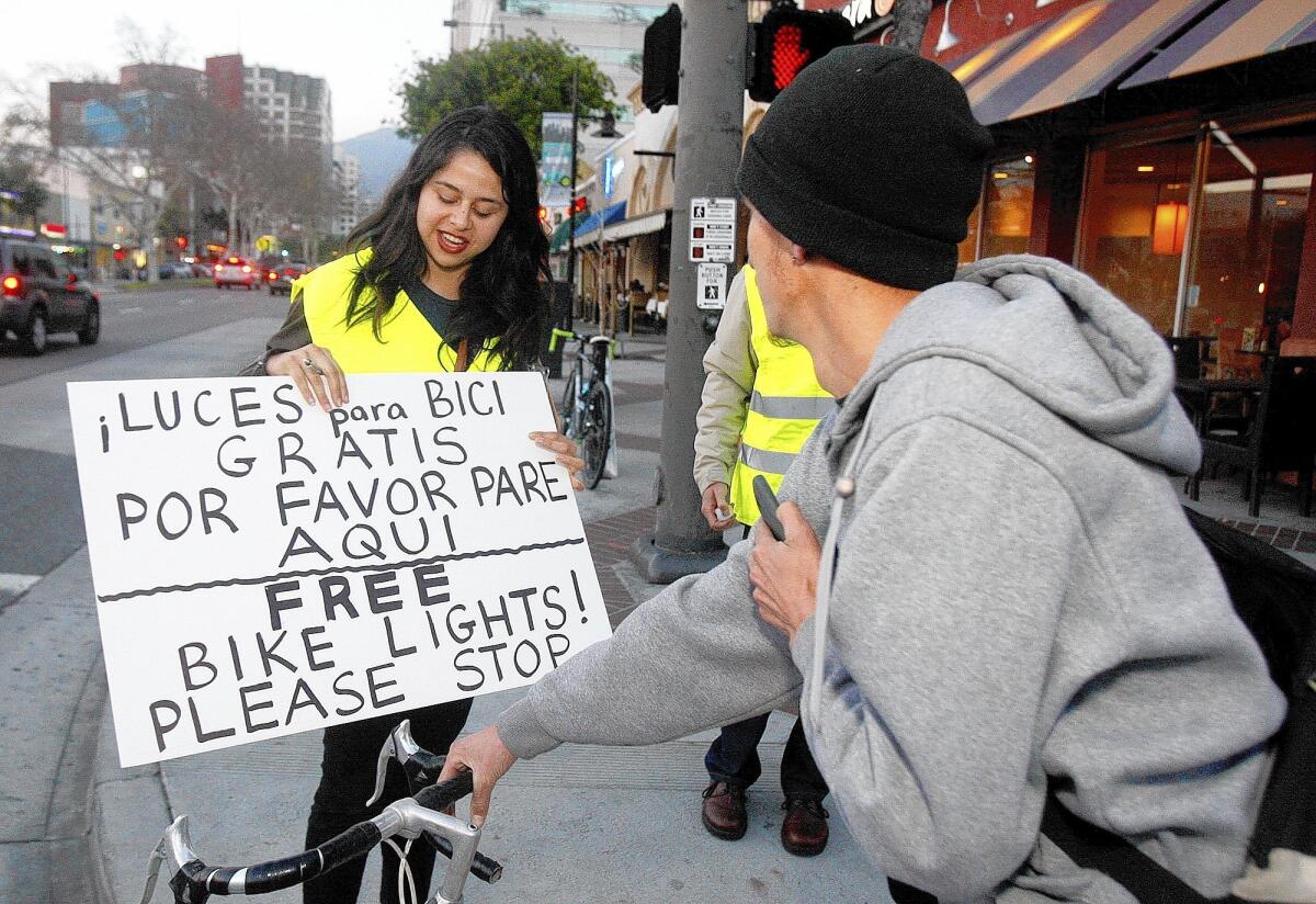 Jenny Morataya, 22, of Walk Bike Glendale and the Los Angeles Bicycle Coalition, talks with Roberto Ruiz, of Glendale. She and a team of volunteers stopped to talk with him about bicycle safety on the corner of California Avenue and Brand Boulevard in Glendale as part of Operation Firefly, photographed on Tuesday, March 4, 2014. Volunteers with Operation Firefly, flagged down passing bicyclists who didn't have front and rear lights, to interview them and give them the free safety equipment.