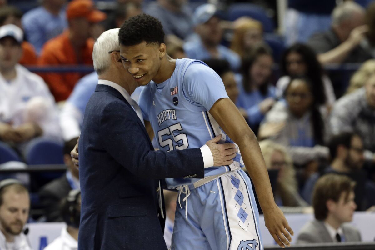 North Carolina head coach Roy Williams hugs North Carolina guard Christian Keeling (55) during the second half of an NCAA college basketball game against Virginia Tech at the Atlantic Coast Conference tournament in Greensboro, N.C., Tuesday, March 10, 2020. (AP Photo/Gerry Broome)
