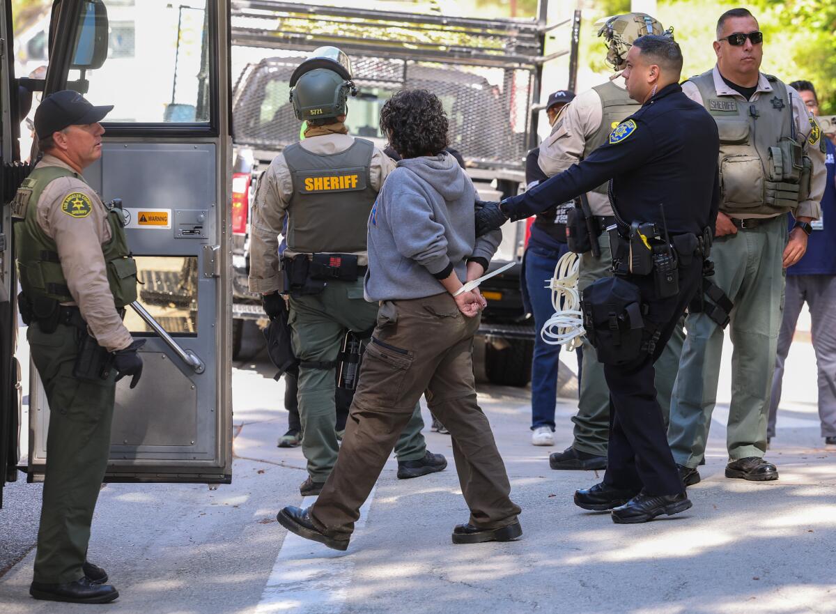 A person arrested at UCLA walks with police. 