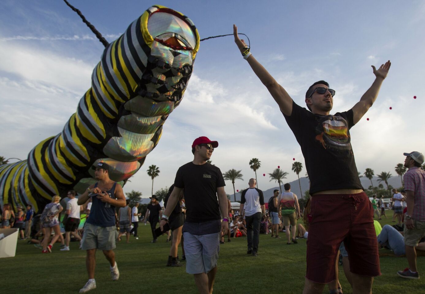 The 2015 Coachella Valley Music and Arts Festival gets underway. Jonathan Martinez holds his hands high in front of the giant Caterpillar Papilio Merraculous.