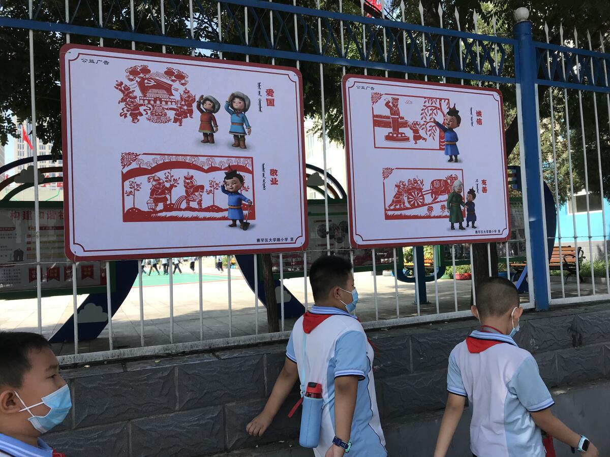 Elementary school students in Hohhot walk past a bilingual sign promoting patriotism and other "Chinese values." 