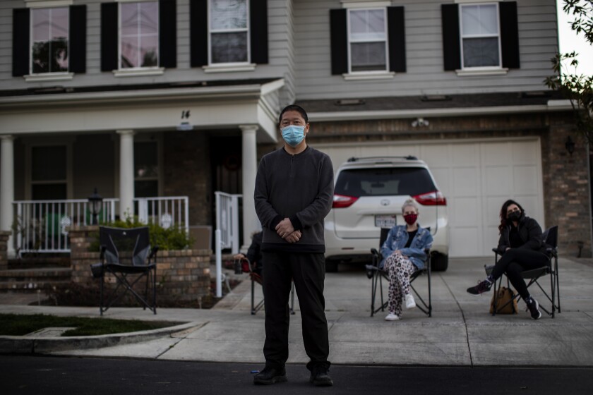 Haijun Si stands in front of his Ladera Ranch home as neighbors gather in front to form a nightly security detail on Feb. 25.
