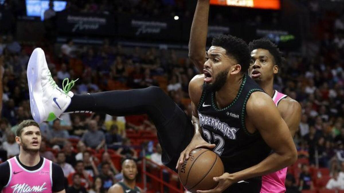 Minnesota Timberwolves center Karl-Anthony Towns (32) goes to the basket as Miami Heat center Hassan Whiteside, right, defends during the first half.