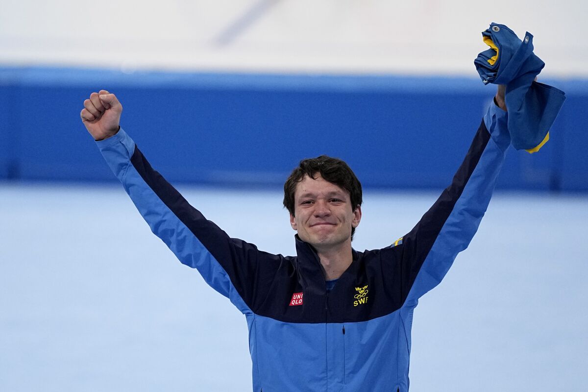 Nils van der Poel of Sweden celebrates his gold medal and Olympic record during a flower ceremony for the men's speedskating 5,000-meter race at the 2022 Winter Olympics, Sunday, Feb. 6, 2022, in Beijing. (AP Photo/Sue Ogrocki)