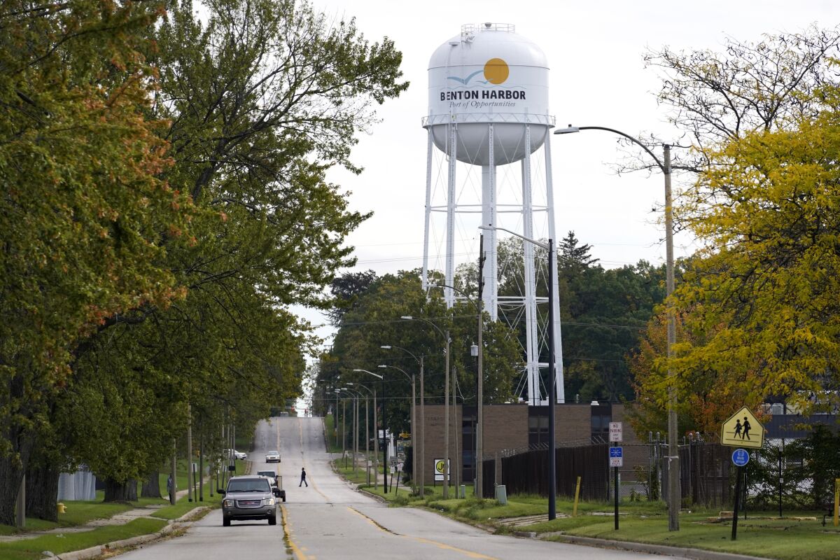 FILE - In this Friday, Oct. 22, 2021 file photo, a lone resident of Benton Harbor, Mich., walks across Britain Street Friday, Oct. 22, 2021, near the city's water tower in Benton Harbor. The water system in Benton Harbor has tested for elevated levels of lead for three consecutive years. (AP Photo/Charles Rex Arbogast, File)