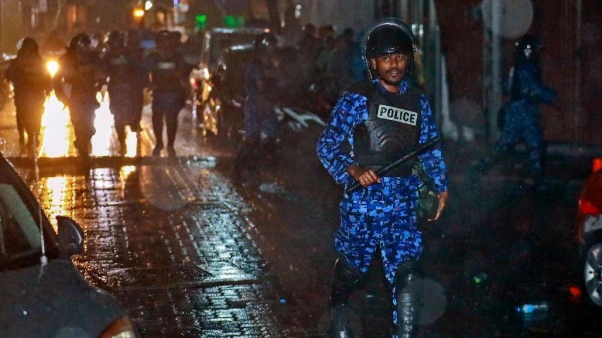 A Maldives policeman charges toward protesters after the government declared a state of emergency early Tuesday.